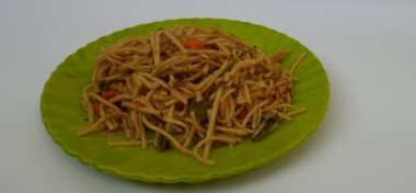 Beyaz arka planda izole edilmiş yeşil bir tabakta ev yapımı lezzetli erişte yığını.