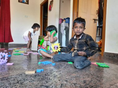 Bangalore, Karnataka, Hindistan-Mar 13 2021: Bir grup çocuk İngiliz alfabesini kullanarak oyun oynuyor ve evin içinde lastik veya köpük minderi numaralandırıyor.