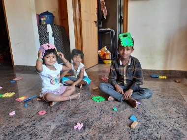 Bangalore, Karnataka, Hindistan-Mar 13 2021: Bir grup çocuk İngiliz alfabesini kullanarak oyun oynuyor ve evin içinde lastik veya köpük minderi numaralandırıyor.