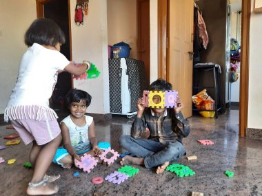 Bangalore, Karnataka, Hindistan-Mar 13 2021: Bir grup çocuk İngiliz alfabesini kullanarak oyun oynuyor ve evin içinde lastik veya köpük minderi numaralandırıyor.