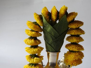 Kasımpatı çiçeği, yaprak, hindistancevizi, kumkum ve zerdeçal ile süslenmiş gümüş kalaş kapağı beyaz arka planda izole edilmiş bir tabakta Ganesha, lakshmi ve shivalinga heykeli.