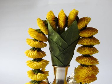 Kasımpatı çiçeği, yaprak, hindistancevizi, kumkum ve zerdeçal ile süslenmiş gümüş kalaş kapağı beyaz arka planda izole edilmiş bir tabakta Ganesha, lakshmi ve shivalinga heykeli.