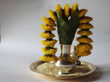 Kasımpatı çiçeği, yaprak, hindistancevizi, kumkum ve zerdeçal ile süslenmiş gümüş kalaş kapağı beyaz arka planda izole edilmiş bir tabakta Ganesha, lakshmi ve shivalinga heykeli.