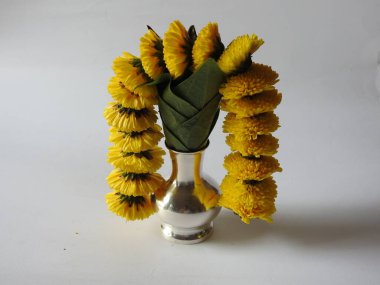 Kasımpatı çiçeği, yaprak, hindistancevizi, kumkum ve zerdeçal ile süslenmiş gümüş kalaş kapağı beyaz arka planda izole edilmiş bir tabakta Ganesha, lakshmi ve shivalinga heykeli.