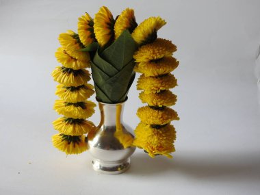 Kasımpatı çiçeği, yaprak, hindistancevizi, kumkum ve zerdeçal ile süslenmiş gümüş kalaş kapağı beyaz arka planda izole edilmiş bir tabakta Ganesha, lakshmi ve shivalinga heykeli.