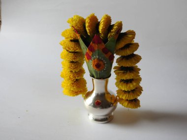 Kasımpatı çiçeği, yaprak, hindistancevizi, kumkum ve zerdeçal ile süslenmiş gümüş kalaş kapağı beyaz arka planda izole edilmiş bir tabakta Ganesha, lakshmi ve shivalinga heykeli.