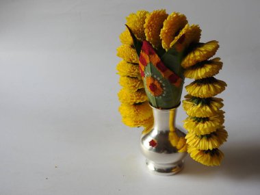 Kasımpatı çiçeği, yaprak, hindistancevizi, kumkum ve zerdeçal ile süslenmiş gümüş kalaş kapağı beyaz arka planda izole edilmiş bir tabakta Ganesha, lakshmi ve shivalinga heykeli.