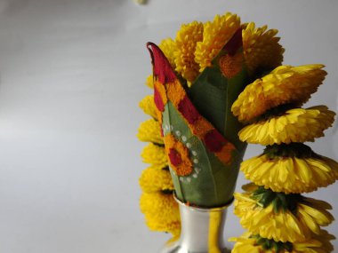 Kasımpatı çiçeği, yaprak, hindistancevizi, kumkum ve zerdeçal ile süslenmiş gümüş kalaş kapağı beyaz arka planda izole edilmiş bir tabakta Ganesha, lakshmi ve shivalinga heykeli.