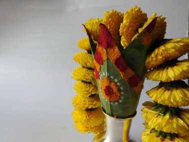 Kasımpatı çiçeği, yaprak, hindistancevizi, kumkum ve zerdeçal ile süslenmiş gümüş kalaş kapağı beyaz arka planda izole edilmiş bir tabakta Ganesha, lakshmi ve shivalinga heykeli.