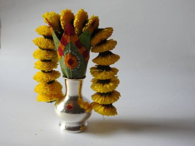 Kasımpatı çiçeği, yaprak, hindistancevizi, kumkum ve zerdeçal ile süslenmiş gümüş kalaş kapağı beyaz arka planda izole edilmiş bir tabakta Ganesha, lakshmi ve shivalinga heykeli.