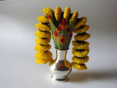 Kasımpatı çiçeği, yaprak, hindistancevizi, kumkum ve zerdeçal ile süslenmiş gümüş kalaş kapağı beyaz arka planda izole edilmiş bir tabakta Ganesha, lakshmi ve shivalinga heykeli.