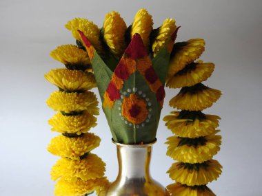 Kasımpatı çiçeği, yaprak, hindistancevizi, kumkum ve zerdeçal ile süslenmiş gümüş kalaş kapağı beyaz arka planda izole edilmiş bir tabakta Ganesha, lakshmi ve shivalinga heykeli.