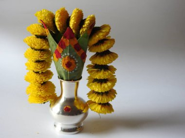 Kasımpatı çiçeği, yaprak, hindistancevizi, kumkum ve zerdeçal ile süslenmiş gümüş kalaş kapağı beyaz arka planda izole edilmiş bir tabakta Ganesha, lakshmi ve shivalinga heykeli.