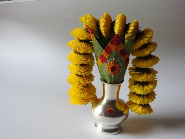 Kasımpatı çiçeği, yaprak, hindistancevizi, kumkum ve zerdeçal ile süslenmiş gümüş kalaş kapağı beyaz arka planda izole edilmiş bir tabakta Ganesha, lakshmi ve shivalinga heykeli.