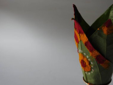 Kasımpatı çiçeği, yaprak, hindistancevizi, kumkum ve zerdeçal ile süslenmiş gümüş kalaş kapağı beyaz arka planda izole edilmiş bir tabakta Ganesha, lakshmi ve shivalinga heykeli.