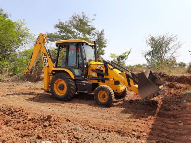Bangalore, Karnataka, India-Mar 21 2021: Closeup of JCB cleaning land for construction of building at forest or countryside