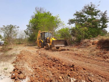 Bangalore, Karnataka, India-Mar 21 2021: Closeup of JCB cleaning land for construction of building at forest or countryside