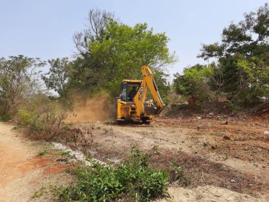 Bangalore, Karnataka, India-Mar 21 2021: Closeup of JCB cleaning land for construction of building at forest or countryside