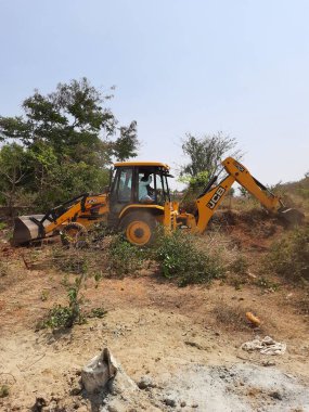 Bangalore, Karnataka, India-Mar 21 2021: Closeup of JCB cleaning land for construction of building at forest or countryside