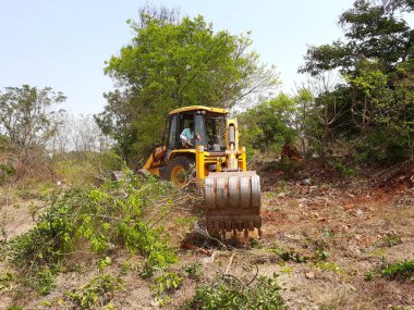 Bangalore, Karnataka, India-Mar 21 2021: Closeup of JCB cleaning land for construction of building at forest or countryside