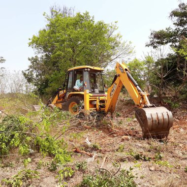 Bangalore, Karnataka, India-Mar 21 2021: Closeup of JCB cleaning land for construction of building at forest or countryside