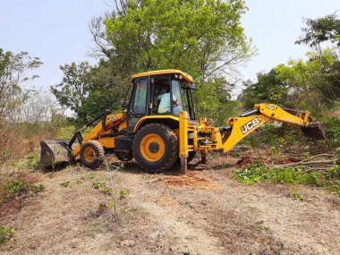 Bangalore, Karnataka, India-Mar 21 2021: Closeup of JCB cleaning land for construction of building at forest or countryside