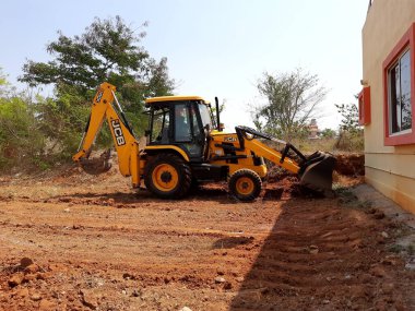 Bangalore, Karnataka, India-Mar 21 2021: Closeup of JCB cleaning land for construction of building at forest or countryside