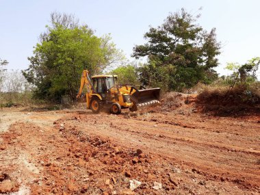 Bangalore, Karnataka, India-Mar 21 2021: Closeup of JCB cleaning land for construction of building at forest or countryside