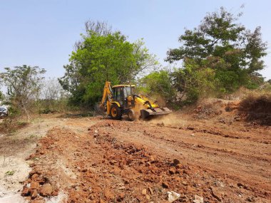 Bangalore, Karnataka, India-Mar 21 2021: Closeup of JCB cleaning land for construction of building at forest or countryside