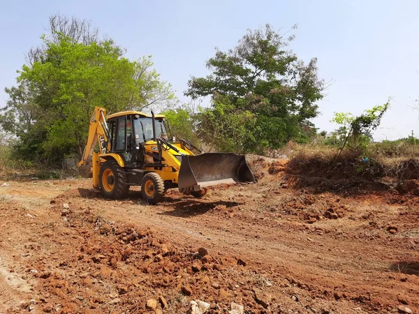 Bangalore, Karnataka, India-Mar 21 2021: Closeup of JCB cleaning land for construction of building at forest or countryside