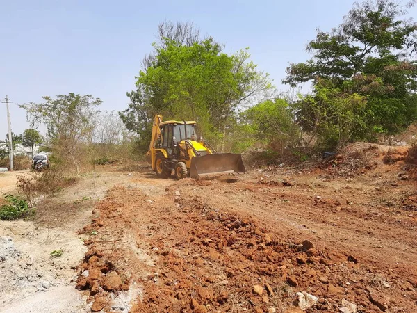 Bangalore, Karnataka, India-Mar 21 2021: Closeup of JCB cleaning land for construction of building at forest or countryside