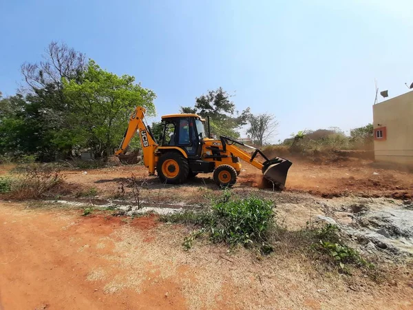 Bangalore, Karnataka, India-Mar 21 2021: Closeup of JCB cleaning land for construction of building at forest or countryside