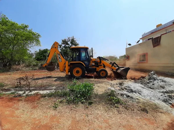 Bangalore, Karnataka, India-Mar 21 2021: Closeup of JCB cleaning land for construction of building at forest or countryside