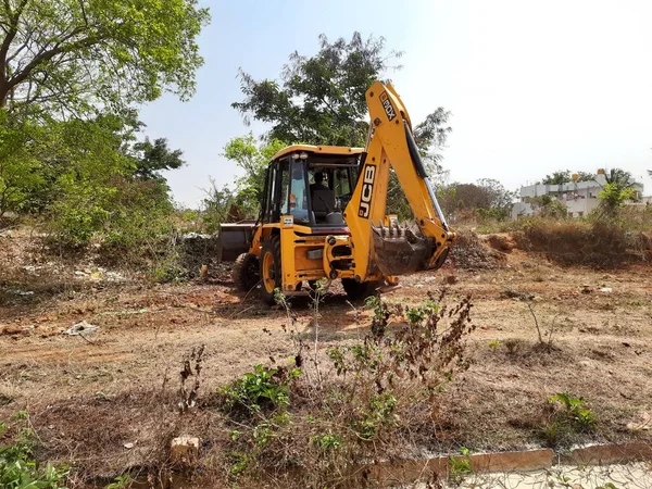 Bangalore, Karnataka, India-Mar 21 2021: Closeup of JCB cleaning land for construction of building at forest or countryside