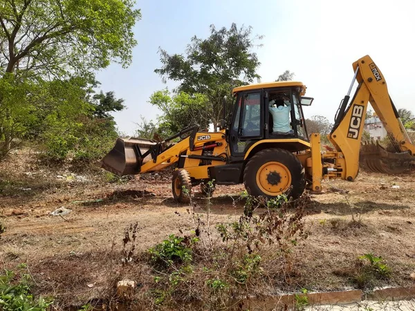 Bangalore, Karnataka, India-Mar 21 2021: Closeup of JCB cleaning land for construction of building at forest or countryside