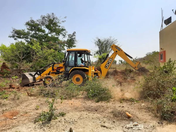 Bangalore, Karnataka, India-Mar 21 2021: Closeup of JCB cleaning land for construction of building at forest or countryside