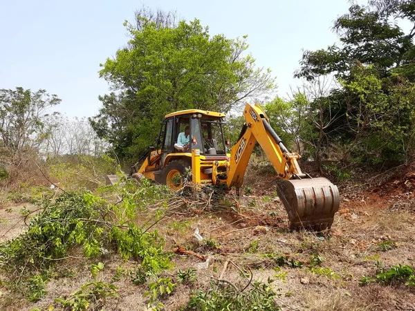 Bangalore, Karnataka, India-Mar 21 2021: Closeup of JCB cleaning land for construction of building at forest or countryside