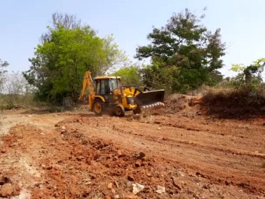 Bangalore, Karnataka, India-Mar 21 2021: Closeup of JCB cleaning land for construction of building at forest or countryside