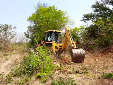 Bangalore, Karnataka, India-Mar 21 2021: Closeup of JCB cleaning land for construction of building at forest or countryside