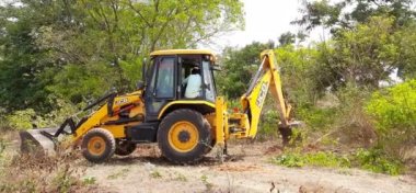 Bangalore, Karnataka, India-Mar 21 2021: Closeup of JCB cleaning land for construction of building at forest or countryside