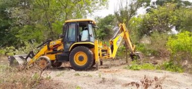 Bangalore, Karnataka, India-Mar 21 2021: Closeup of JCB cleaning land for construction of building at forest or countryside