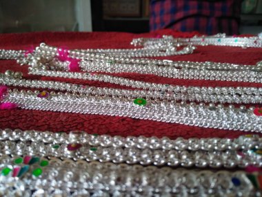 Kırmızı arka planda izole edilmiş bacaklar için gümüş zincir ya da bileklik koleksiyonu.