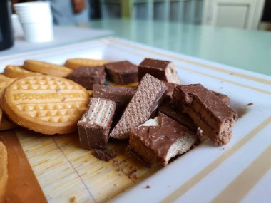 Bangalore, Karnataka, India-Apr 01 2021: Yuvarlak şekilli, tatlı, kaba denetimli bisküvi yığını ve tabakta bir dilim çikolata