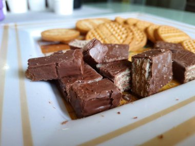 Bangalore, Karnataka, India-Apr 01 2021: Yuvarlak şekilli, tatlı, kaba denetimli bisküvi yığını ve tabakta bir dilim çikolata