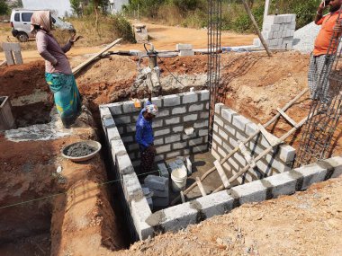 Bangalore, Karnataka, Hindistan-Nisan 10 2021: Hintli işçilerin yeni bina inşaatı, su kuyusu ve inşaat malzemelerini su kullanarak karıştırması.