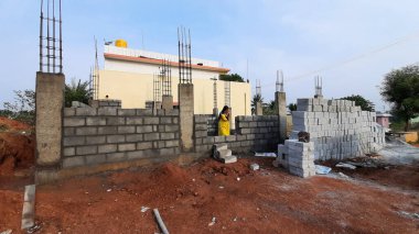 Bangalore, Karnataka, Hindistan-30 Nisan 2021: Yeni bina inşaatı ve temizlik evi gören Hintli genç anne ve çocuğun yakın çekimi