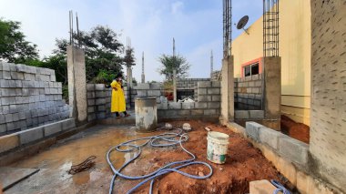 Bangalore, Karnataka, Hindistan-30 Nisan 2021: Yeni bina inşaatı ve temizlik evi gören Hintli genç anne ve çocuğun yakın çekimi