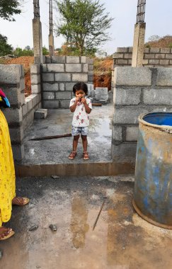 Bangalore, Karnataka, Hindistan-30 Nisan 2021: Yeni bina inşaatı ve temizlik evi gören Hintli genç anne ve çocuğun yakın çekimi