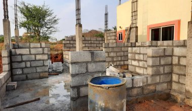 Bangalore, Karnataka, Hindistan-20 Nisan 2021: Yeni konut çimentosu duvar tuğlalarını doğa arka planında sütunlarla örüyor