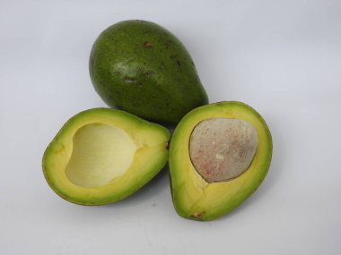 Çiğ tereyağlı meyve veya avokadodan oluşan tek ve yarı dilimlenmiş ve beyaz arka planda izole edilmiş meyveleri tutan bir grup yakın plan.